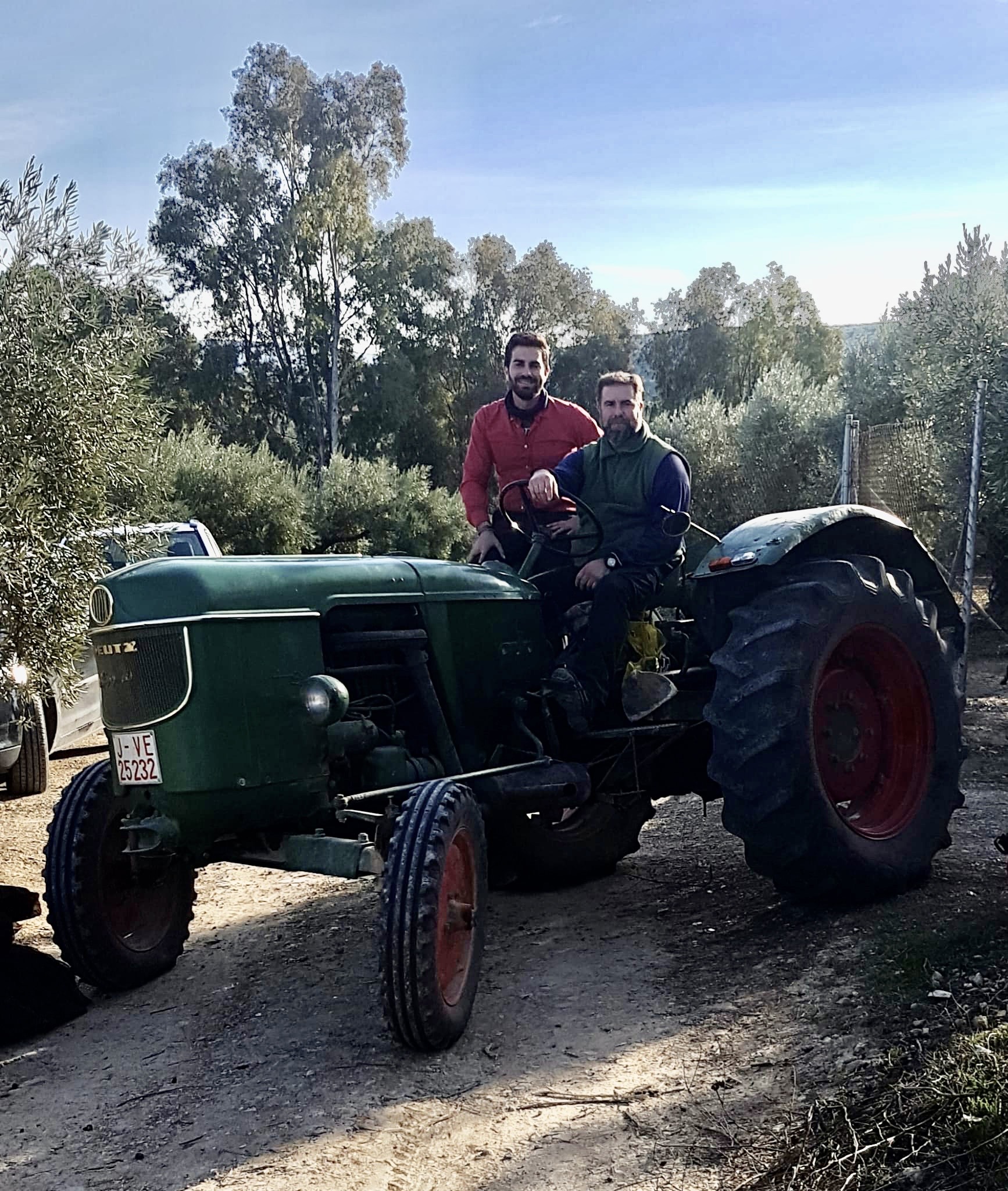 Dos personas junto a un tractor entre olivos